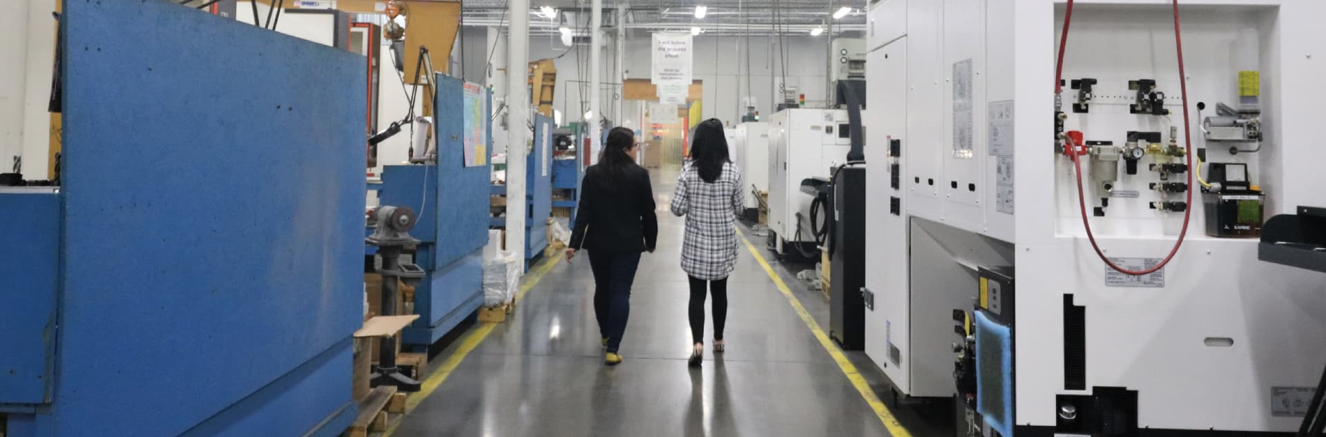 Two Women Walking Through The Mme Production Floor